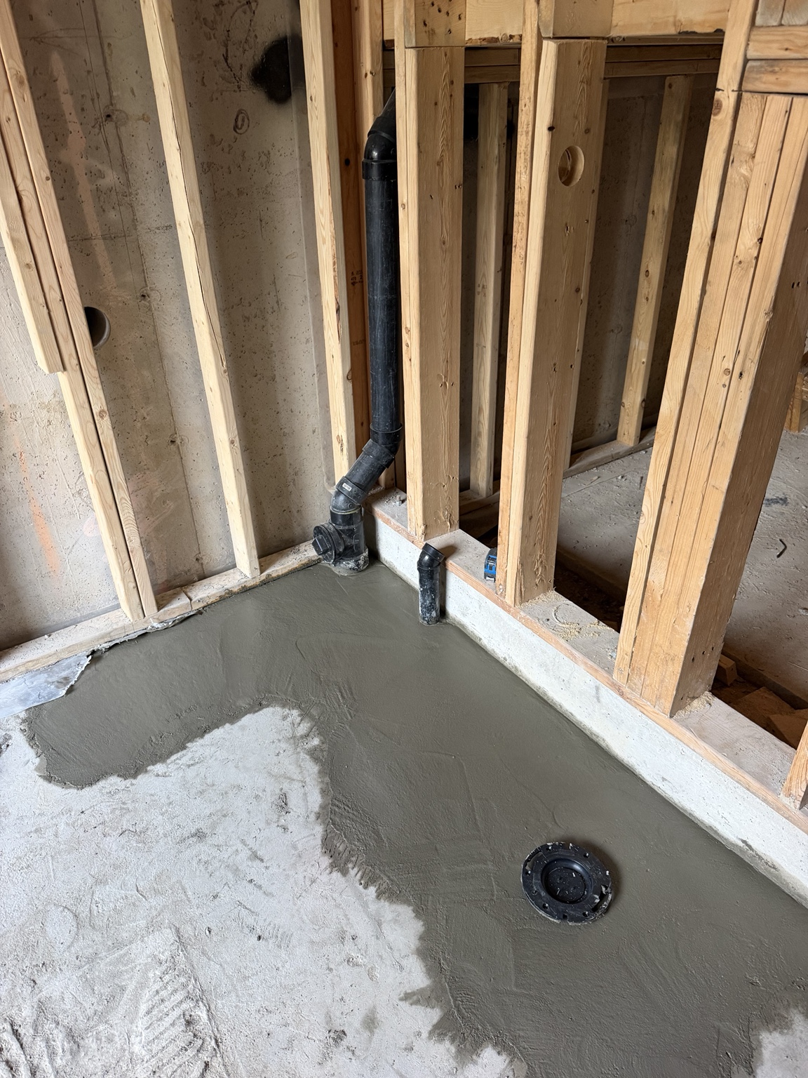 Restored concrete floor around the bathroom drain rough-in