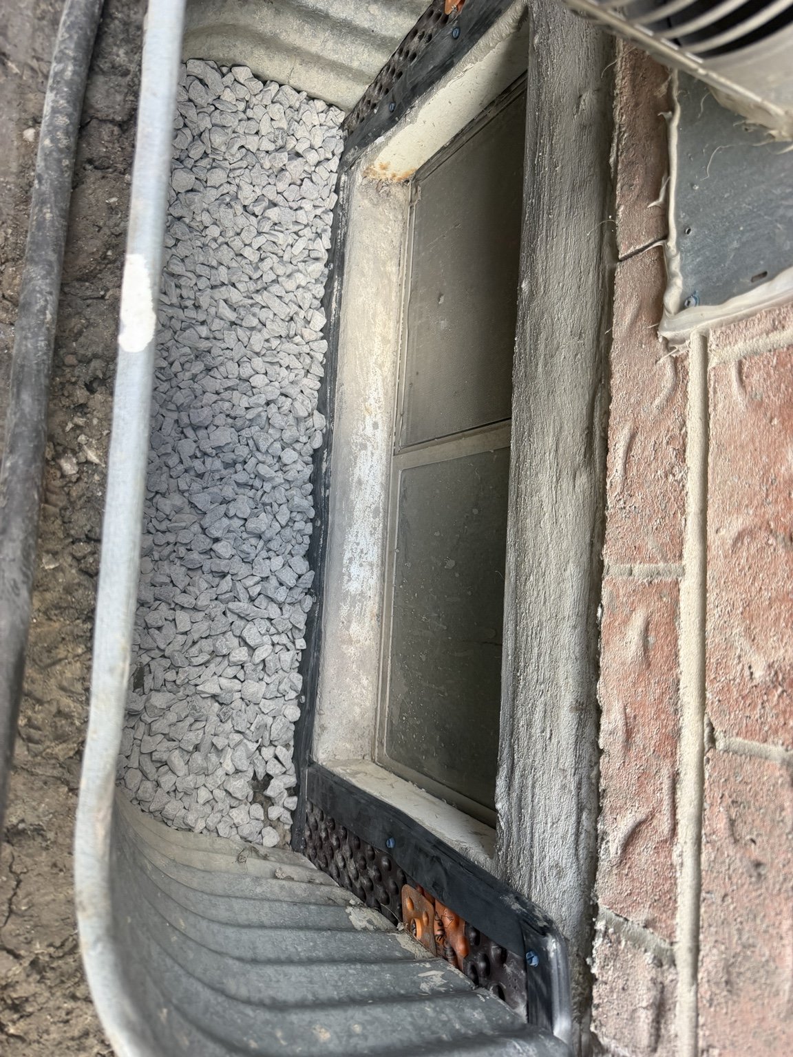 Window well with gravel and foundation membrane
